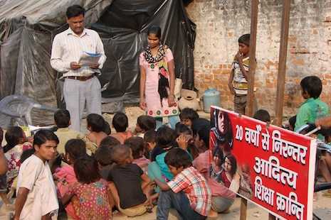 On the back of a bike, Indian teacher brings 'classroom' to slum children