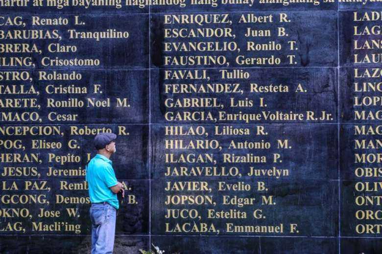 A former political prisoner looks at a Wall of Remembrance in Quezon City, suburban Manila, with the names of victims from the martial law era during the dictatorship of Ferdinand Marcos Sr. in the 1970s