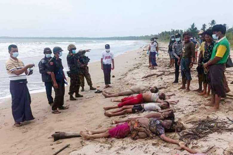 This photo taken on May 22 by an anonymous source shows officials looking at bodies washed up on a beach after a boat carrying at least 90 people capsized near the coast of Pathein township on May 21