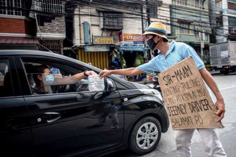 A jeepney driver receives alms from a motorist in Manila in August 2020 as the Philippine economy reeled from coronavirus lockdowns