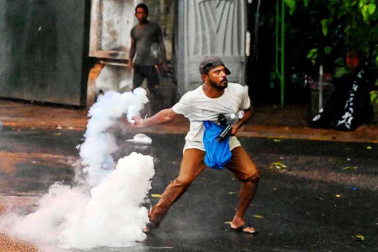 A demonstrator throws back a tear gas canister fired by police to disperse students taking part in an anti-government protest over Sri Lanka's crippling economic crisis in Colombo on May 29