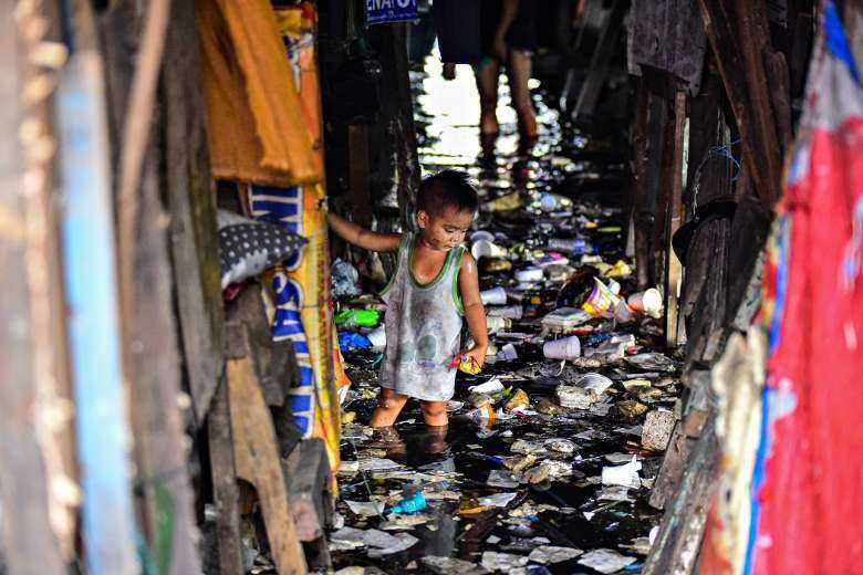 A child wades through the trash-filled and polluted waters of a river running through a slum in Philippine capital Manila