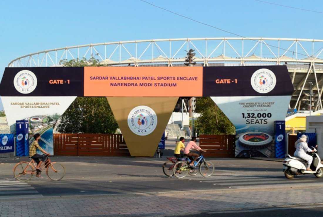 Indians cycle past the main entrance of the Narendra Modi Stadium, a venue for India's popular game of cricket, near Ahmedabad city in Gujarat state on May 4, 2021