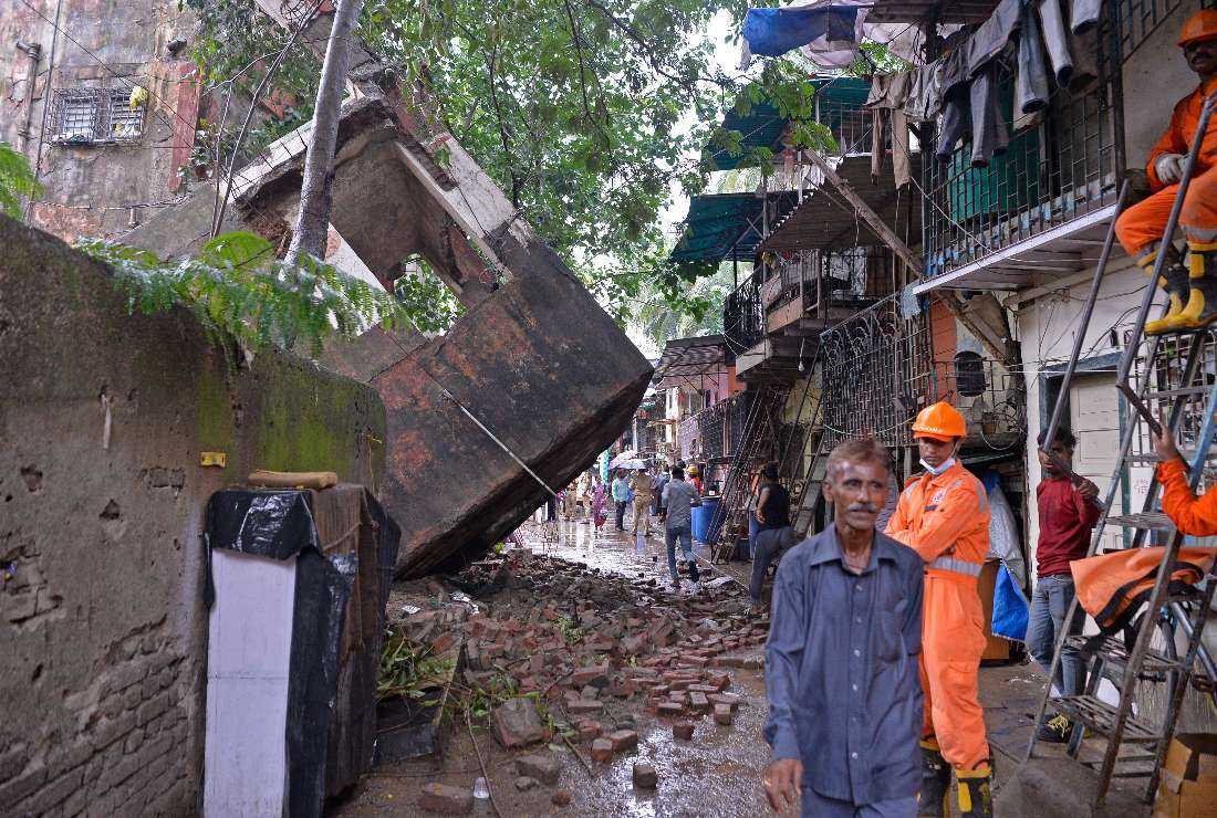 Rescue workers stand beside the collapsed building in Mumbai on June 28
