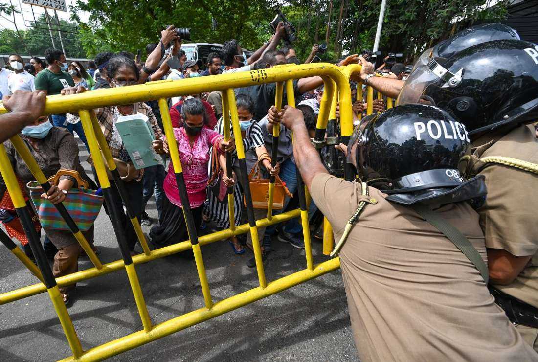 Activists from Samagi Vanitha Balawegaya, part of the main opposition party Samagi Jana Balawegaya, try to overturn a police barricade during a protest outside Prime Minister Ranil Wickremesinghe's residence in Colombo on June 22