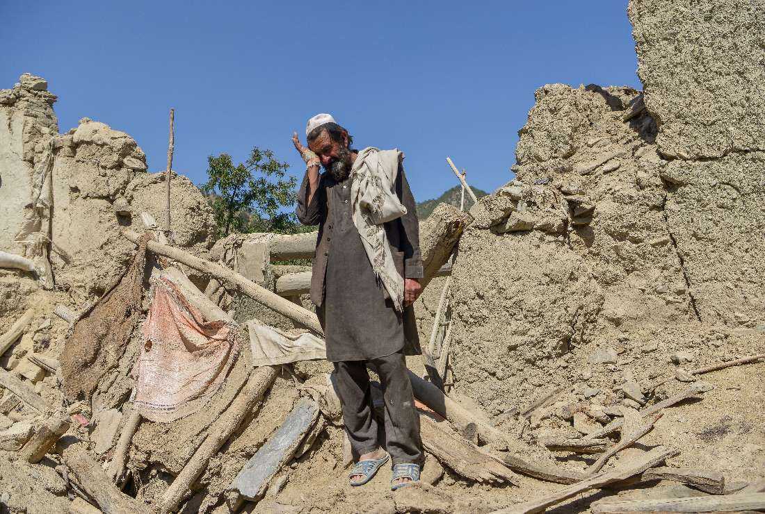 An Afghan man stands besides the ruins of a house damaged after an earthquake in Gayan district, Paktika province, on June 24