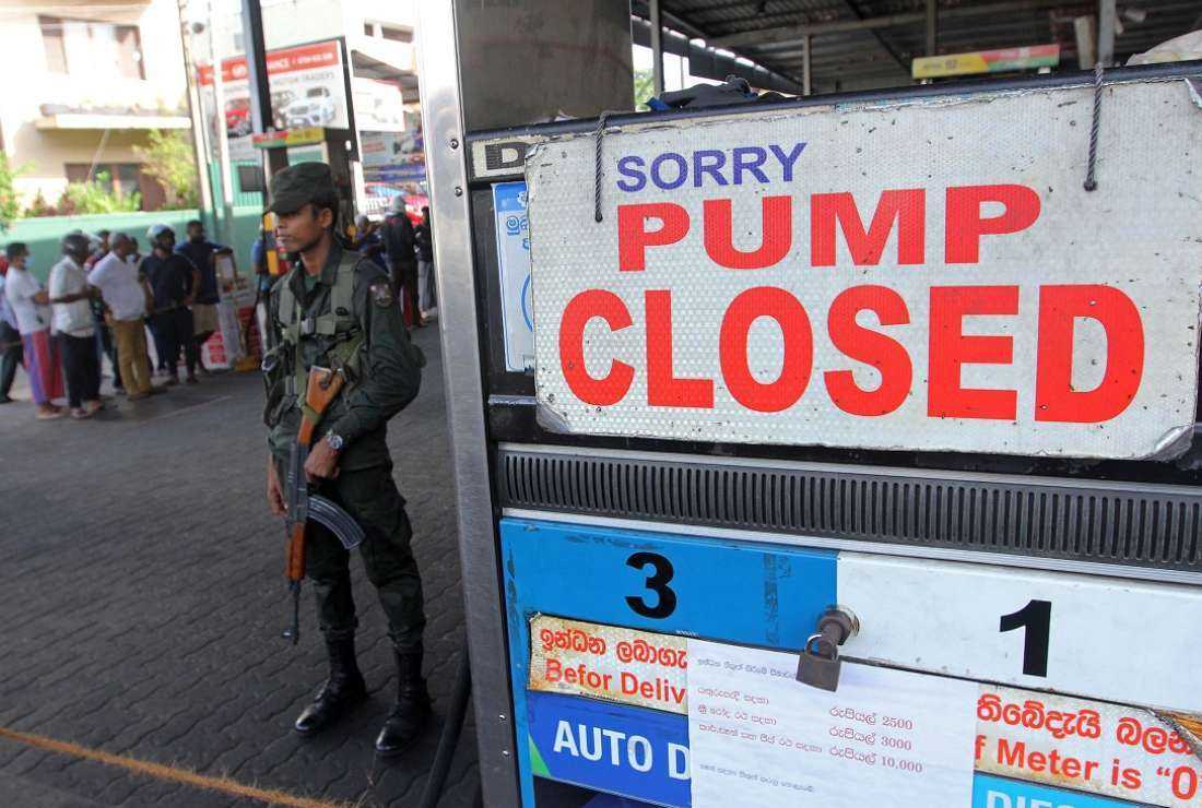 A security officer stands guard outside a fuel station that ran out of gasoline in Colombo on June 27