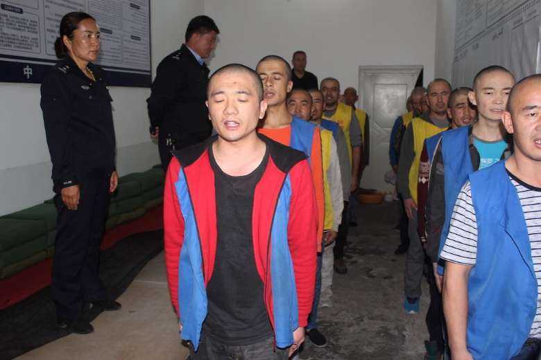 This undated image released on May 24 shows Uyghur detainees guarded by police as they stand in line apparently reciting or singing at Tekes County Detention Centre in Xinjiang, western China. A leak of thousands of photos and official documents has shed new light on the violent methods used to enforce mass internment in the region