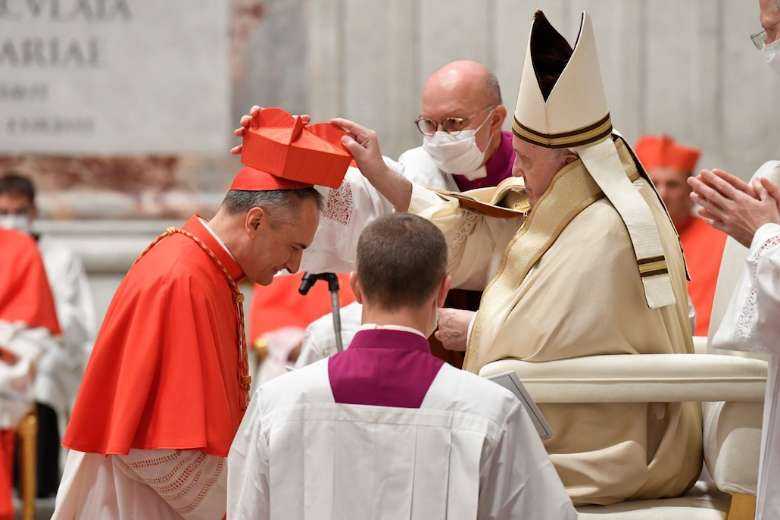 Italian Mauro Gambetti, custos of the Sacred Convent of Assisi, receives his red hat from Pope Francis during a consistory to create 13 new cardinals at St. Peter's Basilica on Nov. 28, 2020