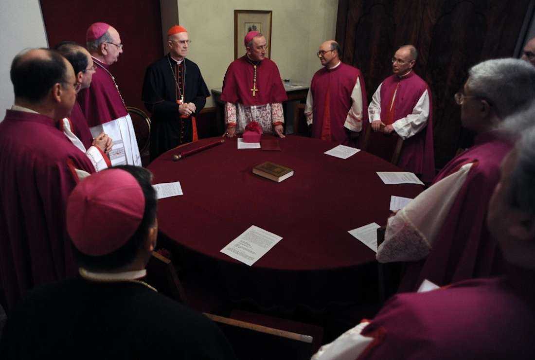 Cardinal Tarcisio Bertone (center) and ecclesiasts pray before closing the door of the pontiff's apartments at the Vatican after the departure of Pope Benedict XVI on Feb. 28, 2013. Pope Benedict had become the first pope to resign in over 700 years