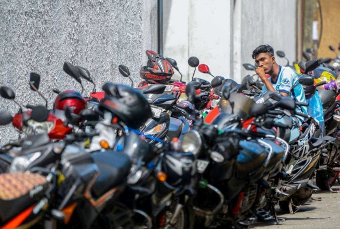 A man waits amongst motorbikes parked in a queue by people waiting to fill up at a gas station in Colombo on July 4
