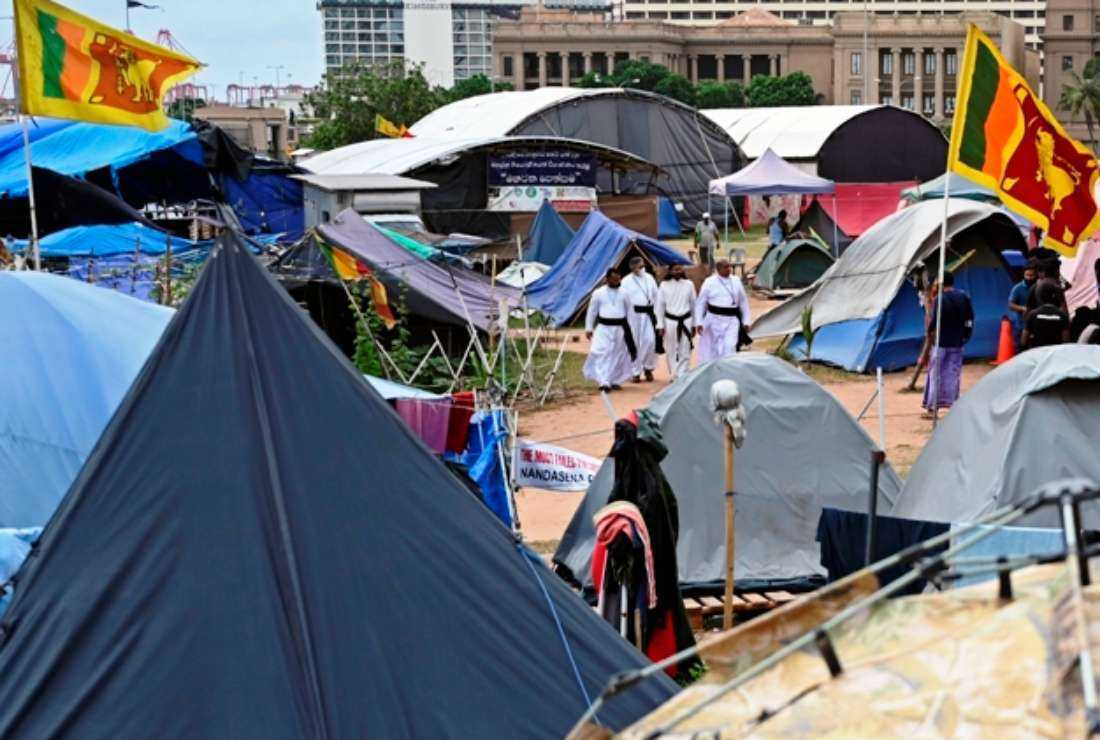 Christian priests walk through the tents installed by the demonstrators near Presidential Secretariat in Colombo on July 24, 2022