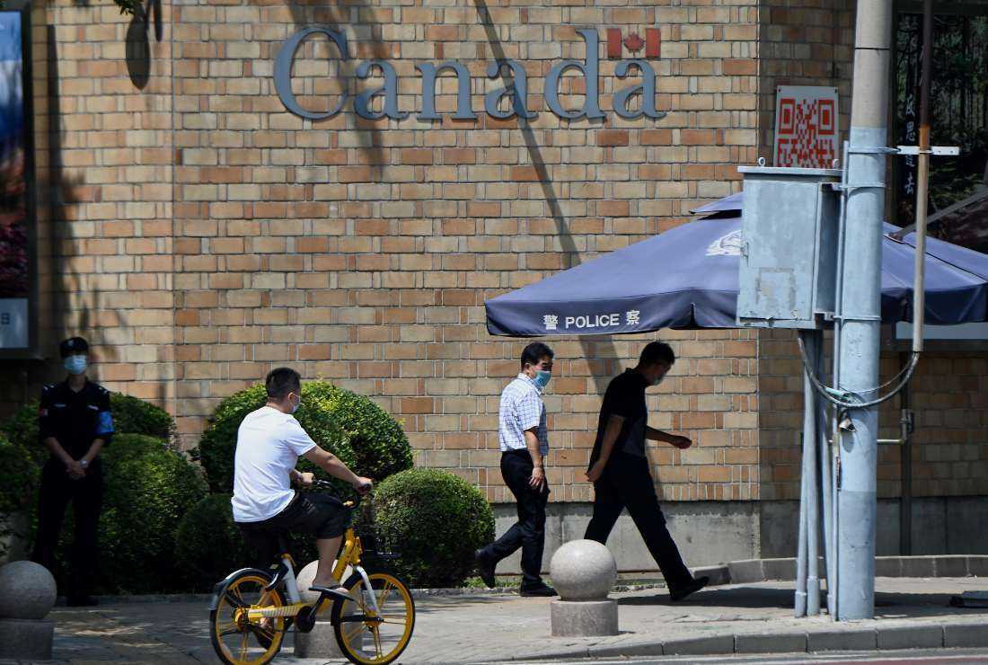 People walk past the Canadian Embassy in Beijing on August 10, 2021