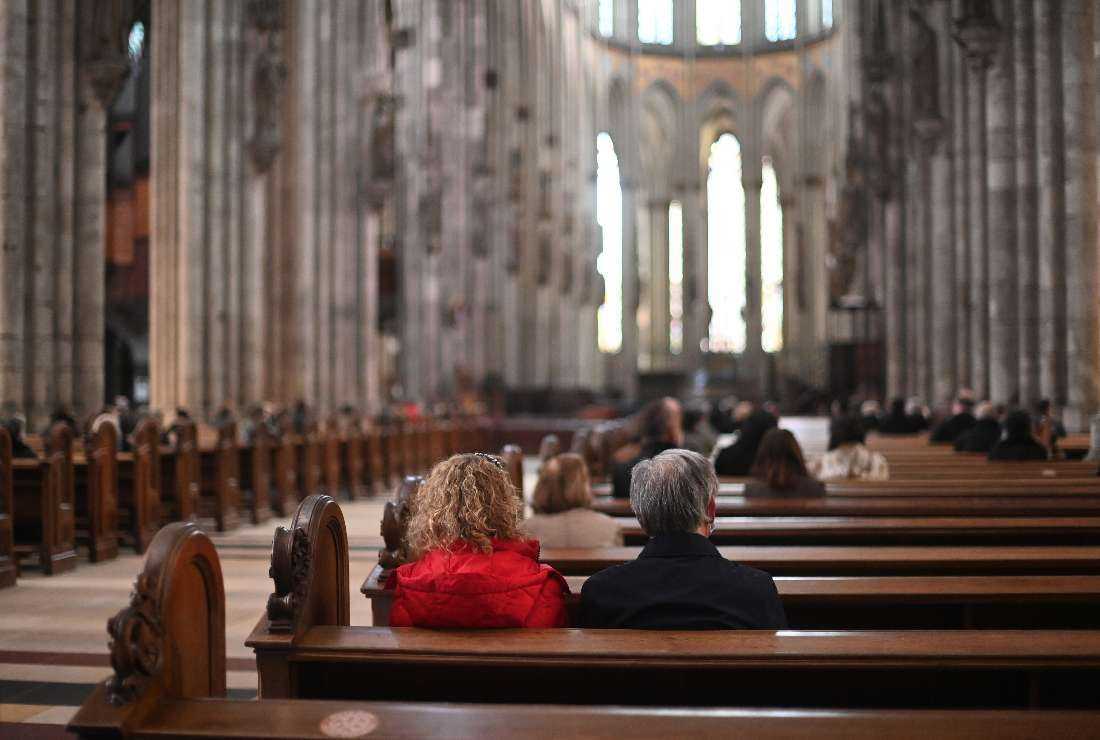 A couple together with other believers attends a mass held by German Cardinal Woelki on Good Friday at a Cathedral in Cologne, western Germany, on April 2, 2021