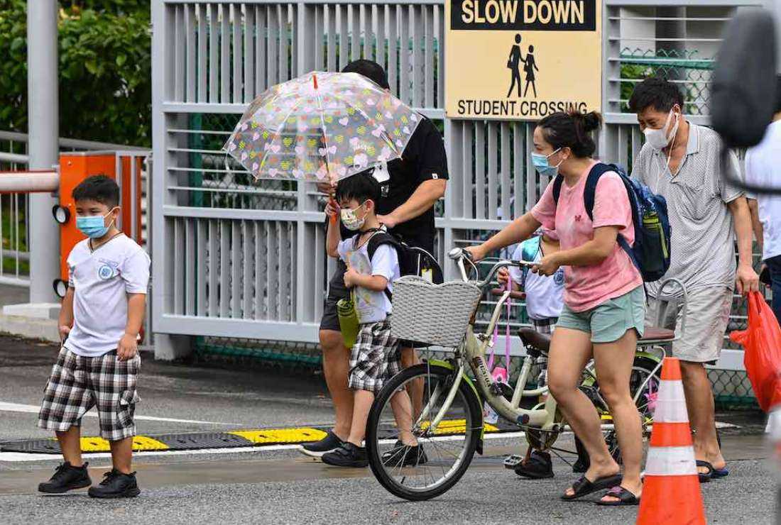 Children walk home with their guardians after school in Singapore on May 17, 2021, as the country prepares to shut all schools and switch to home-based learning until the end of the term due to a rise in the number of Covid-19 coronavirus cases