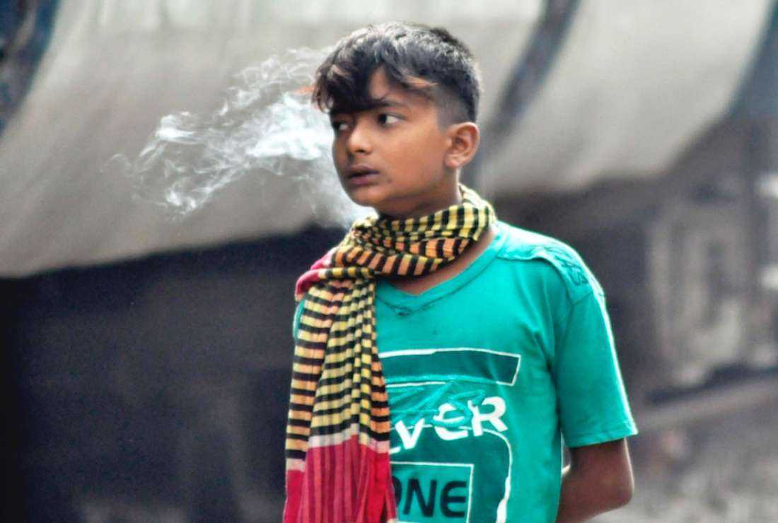 A street child is seen smoking at Kamlapur railway station in Dhaka in 2014