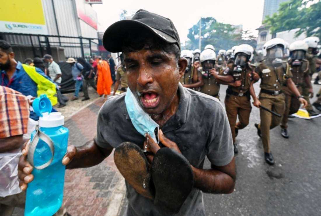 A demonstrator rinses his face with water after police fired tear gas to disperse university students and demonstrators protesting against the Sri Lankan government in Colombo on Aug. 30