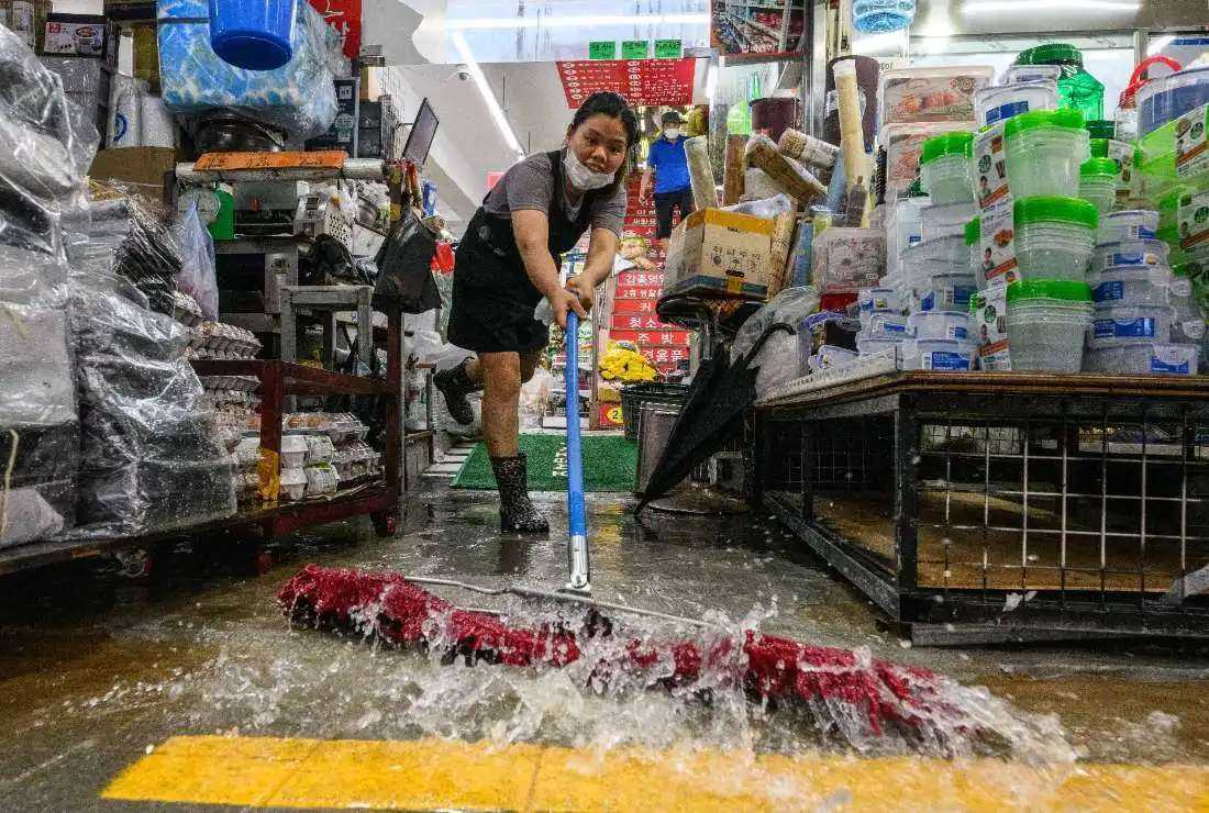 A worker clears water from her shop at the historic Namseong Market in the Gangnam district of Seoul after record-breaking rains caused severe flooding in parts of South Korea, on Aug. 9