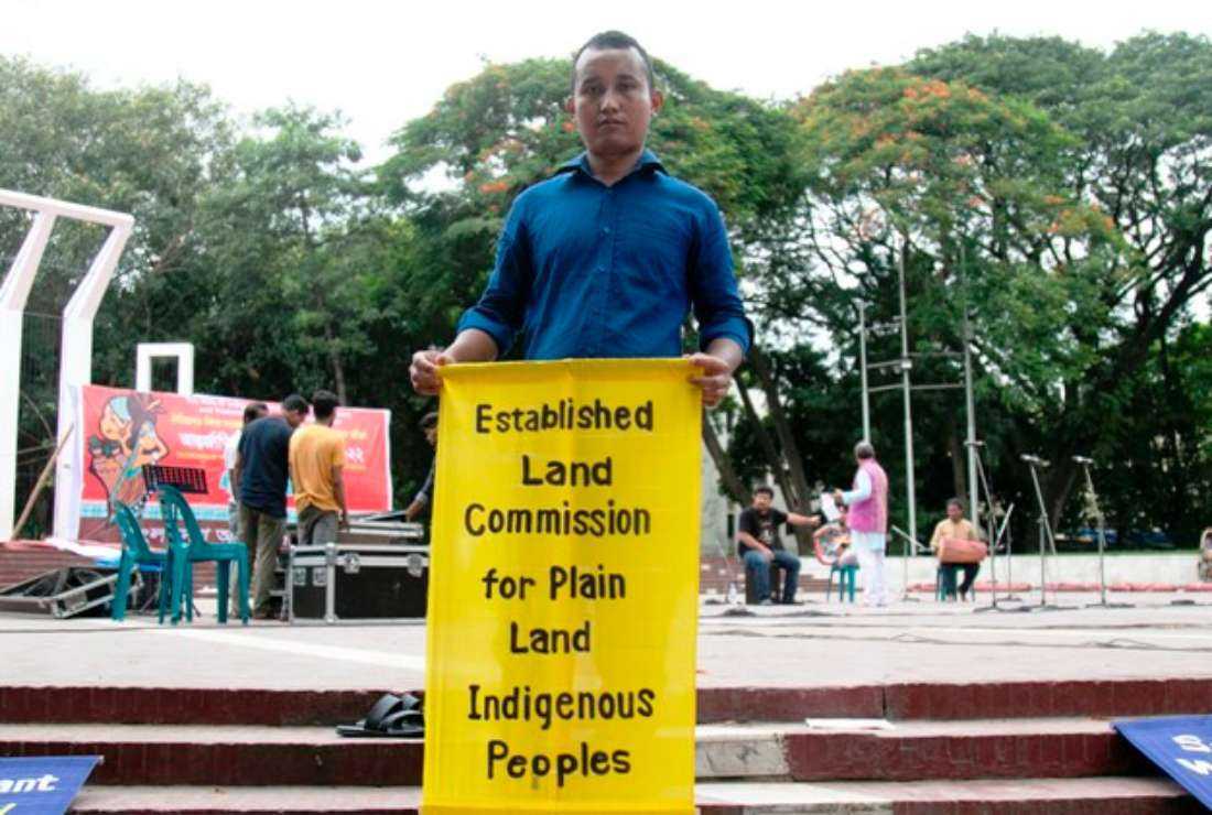 An indigenous man holding a placard demanding resolution of their land issues, in Dhaka on Aug. 19