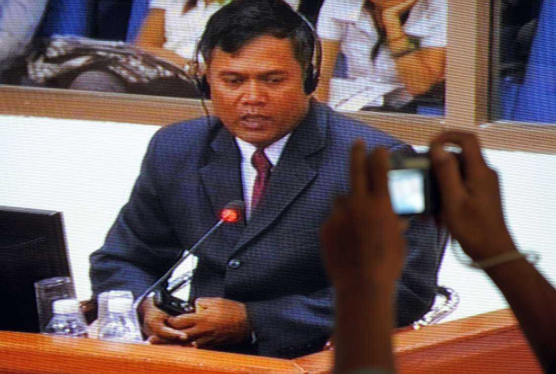 A photographer (right) taking pictures of a television screen broadcasting live video footage of Dr. Sotheara Chhim testifying at the Extraordinary Chambers of the Courts of Cambodia in Phnom Penh on Aug. 25, 2009