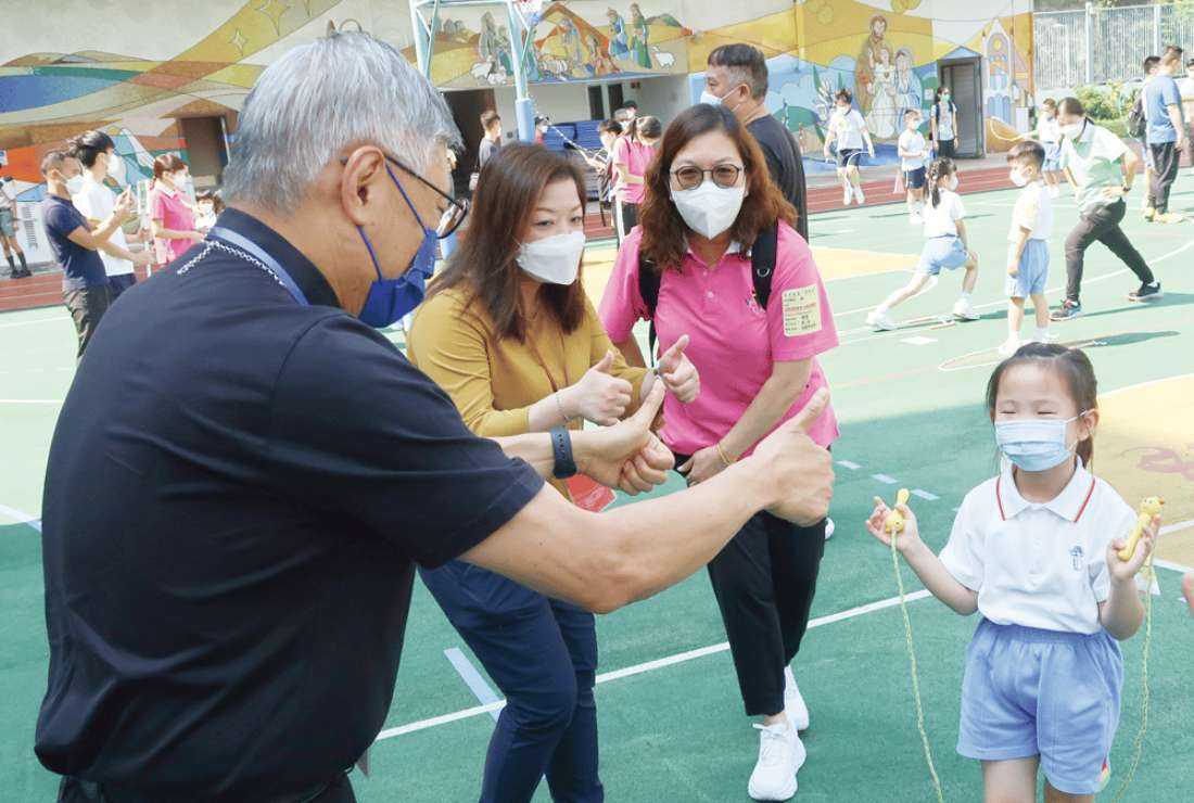 Bishop Stephen Chow Sau-yan of Hong Kong gives a thumbs up to a young kindergarten girl who participated in a rope-skipping charity rally