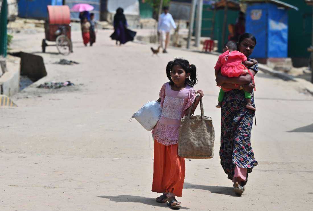 Rohingya people walk along a street after collecting relief materials in Jamtoli refugee camp in Ukhia on March 22