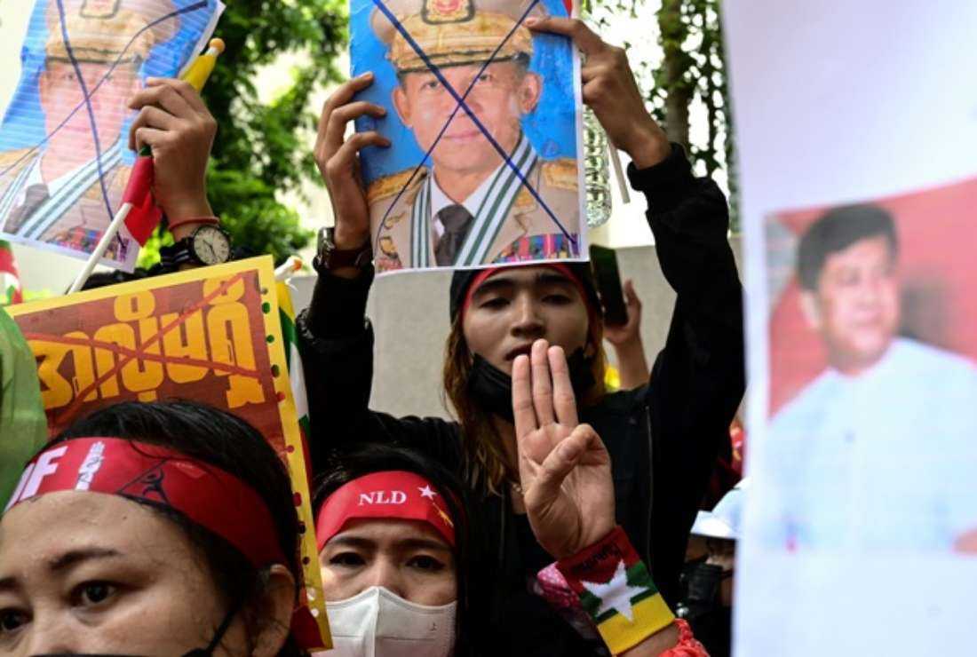 Protesters show the three-finger salute and a crossed-out image of Myanmar military chief Min Aung Hlaing during a demonstration against the Myanmar military junta's execution of four prisoners, outside the Myanmar Embassy in Bangkok on July 26