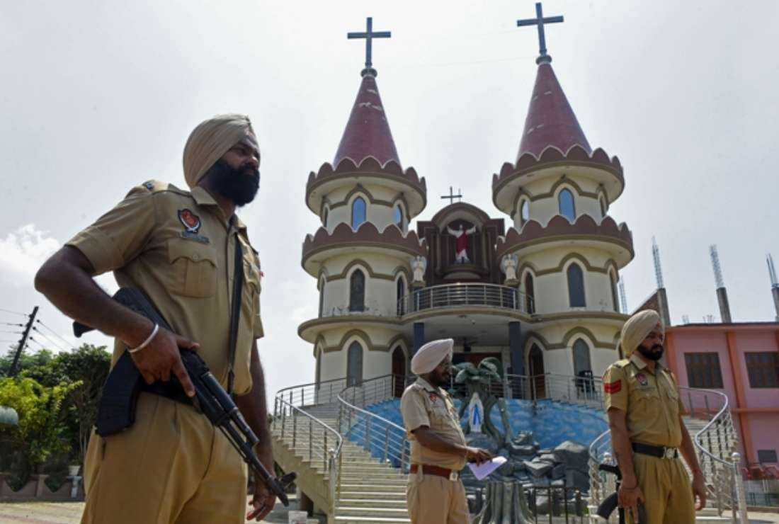 Punjab police stand guard at a church in Amritsar on Sept. 2 following an incident in which four masked men allegedly vandalized a Pieta statue inside the church premises and set a car parked there on fire at Thakarpura village in India's Punjab state