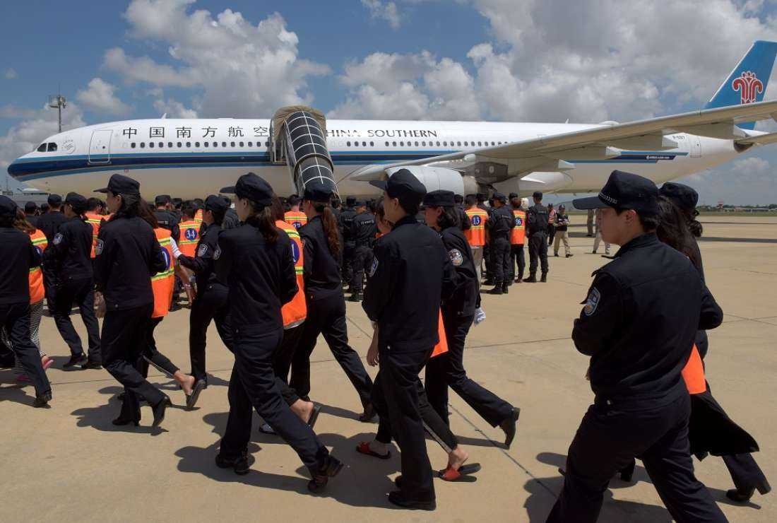 Chinese police escort suspects as they prepare to board a plane at Phnom Penh international airport in this Oct 12, 2017 photo. Cambodia deported 74 Chinese national suspected of running a telecoms scam to extort money from victims in their home country