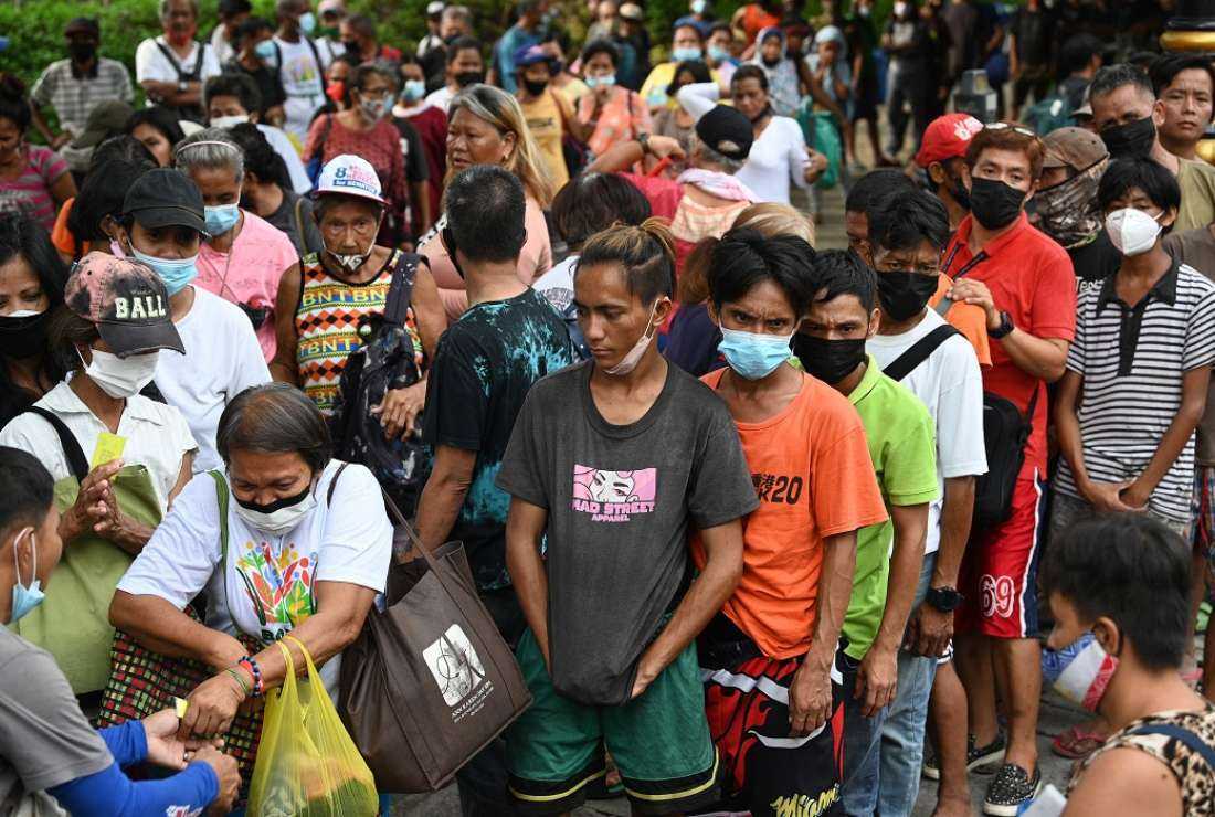 People queue for free packed meals distributed by the Catholic religious order, Society of the Divine Word (SVD), in Manila on June 24, 2022