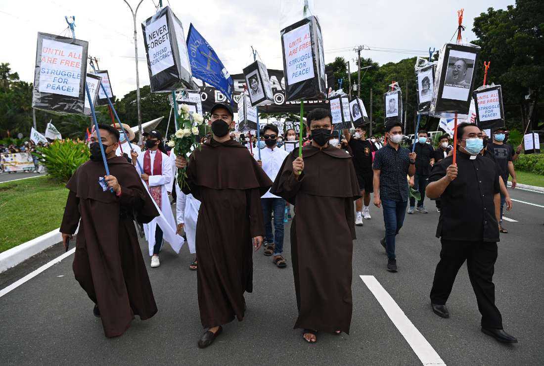 Members of religious group carry placards as they march during a rally to commemorate 50th anniversary of the imposition of martial law at the university grounds in Quezon City, suburban Manila on Sept. 21