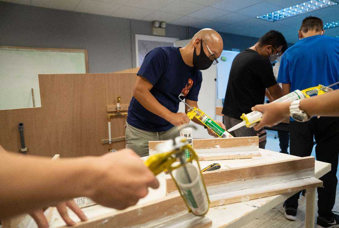 Students practicing caulking skills during a home-repair class in Hong Kong on Sept. 3