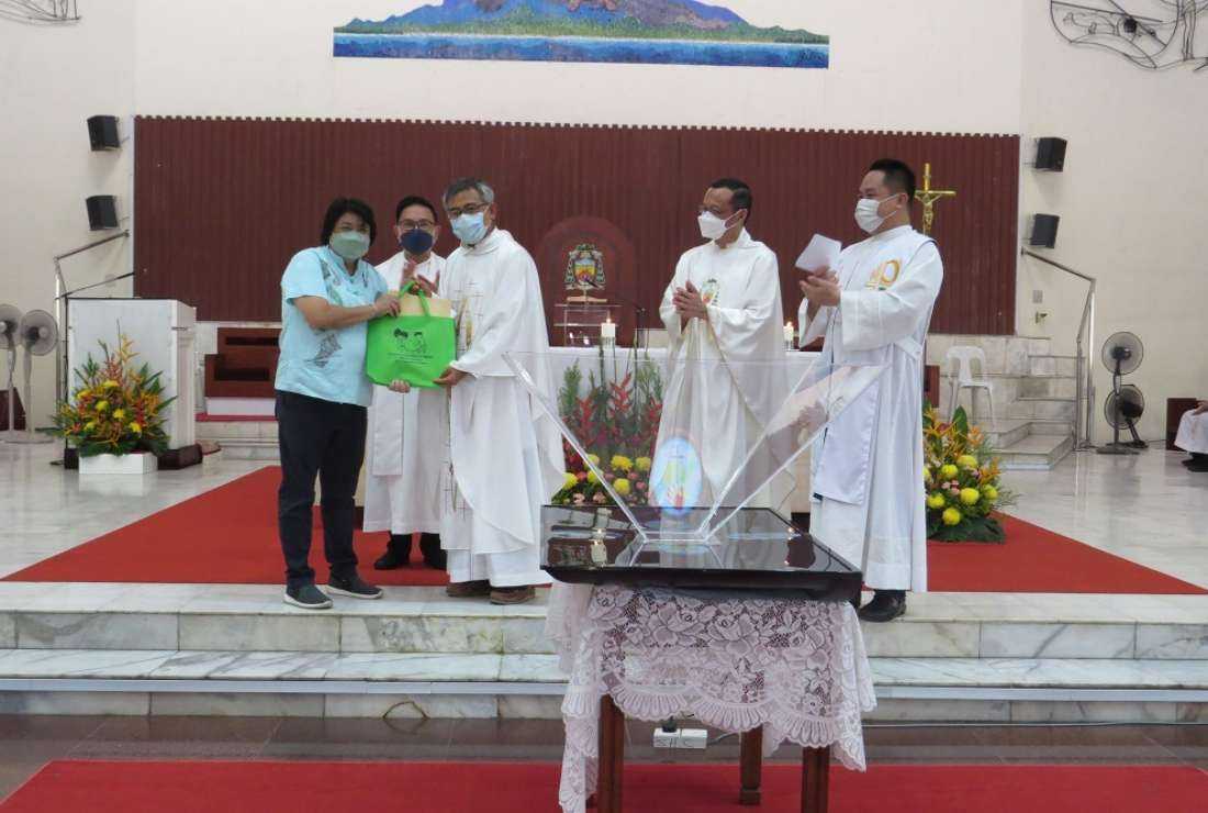 Malaysian Bishop Joseph Hii Teck Kwong presents a poster to a Catholic during the launch of year-long campaign against plastic pollution