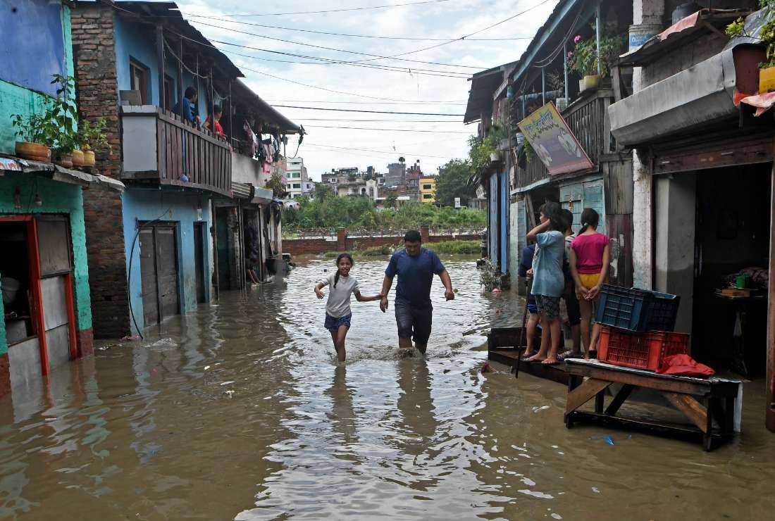 Residents wade through a flooded street after the Bagmati river overflowed following heavy monsoon rains in Kathmandu on Sept. 6, 2021