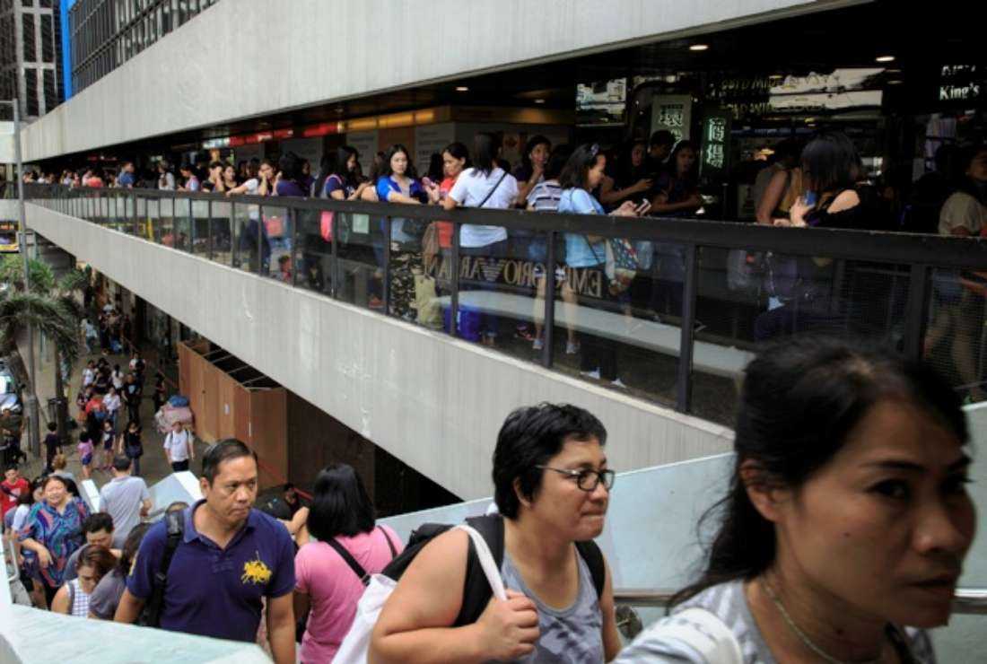 Migrant workers, many of them from the Philippines and employed as domestic maids, are seen amongst pedestrians at a public access walkway as they gather on their weekly Sunday off in Hong Kong's Central district on Sept. 24
