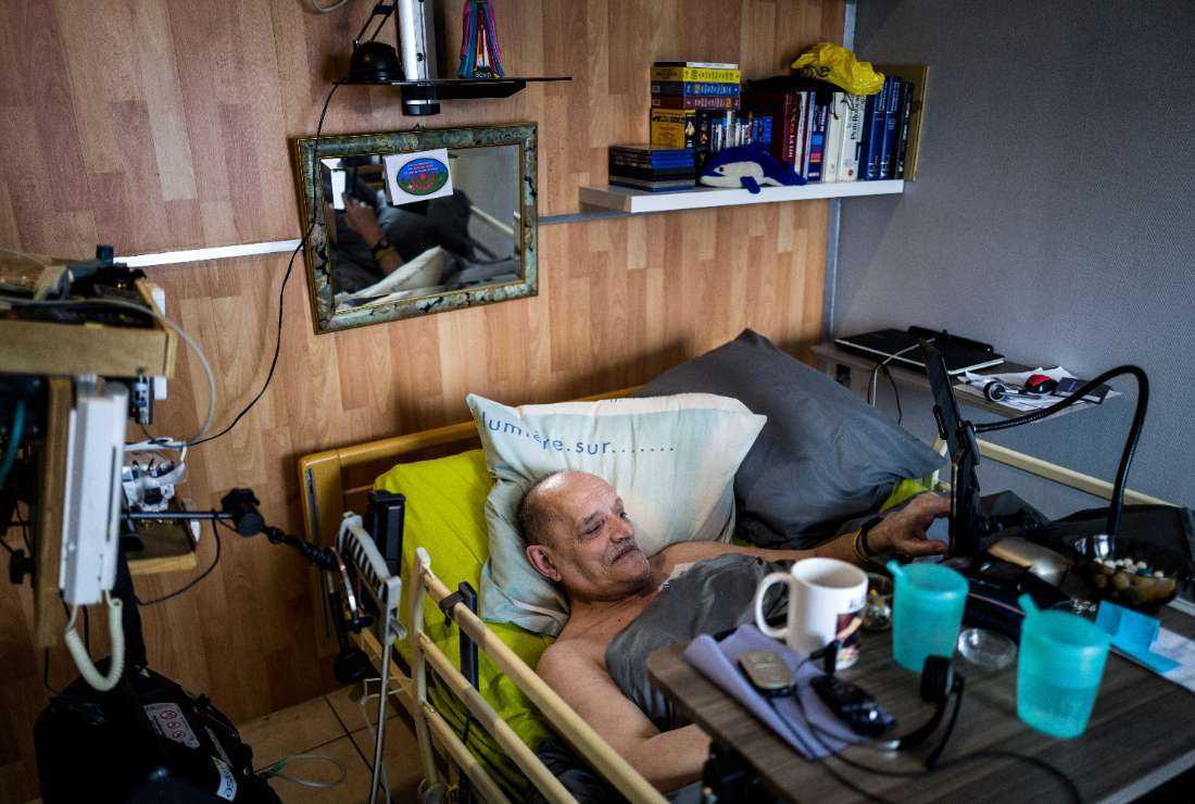 Alain Cocq, suffering from an incurable orphan disease, touches his phone in his medical bed at his home in Dijon on April 6, 2021. The French government plans to legalize euthanasia by the end of 2023