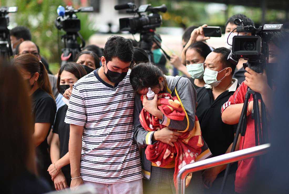Sittipong Taothawong (left) comforts his wife Kanjana Buakumchan as she holds their child's milk bottle and blanket while standing outside the nursery in Na Klang in Thailand's northeastern Nong Bua Lam Phu province on Oct. 7