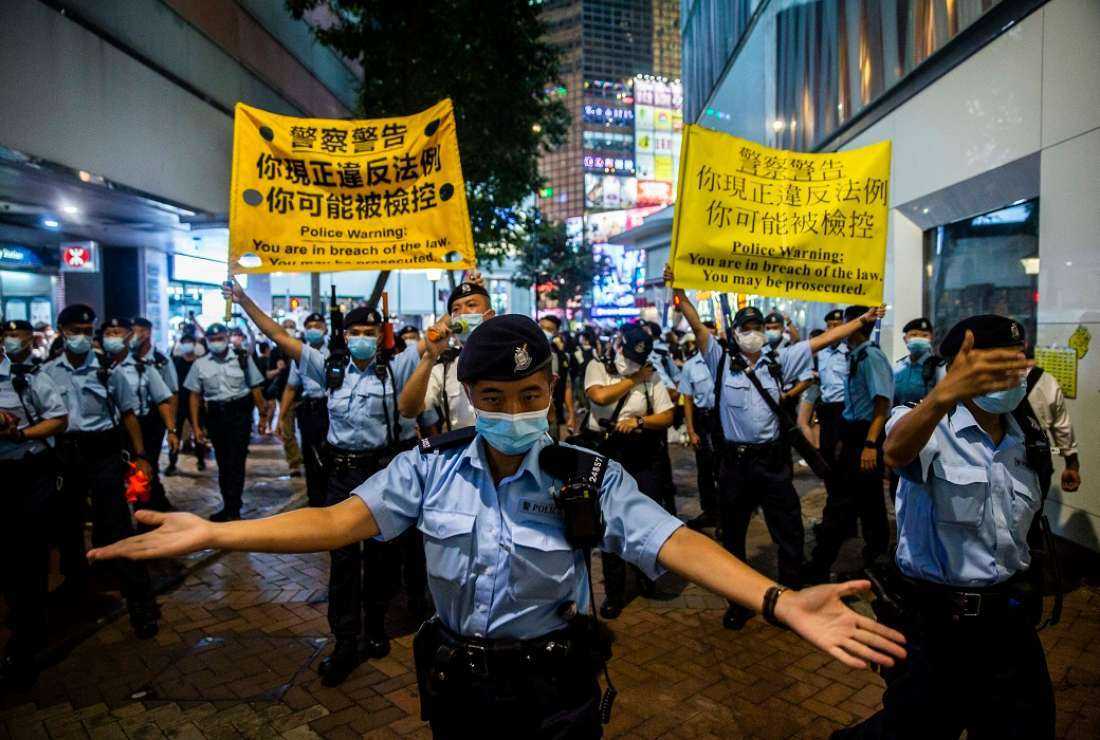 Police move people on as they gathered in the Causeway Bay district of Hong Kong on June 4, 2021, after police closed the venue where Hong Kong people traditionally gather annually to mourn the victims of China's Tiananmen Square crackdown in 1989 which the authorities banned citing the coronavirus pandemic and vowed to stamp out any protests on the anniversary