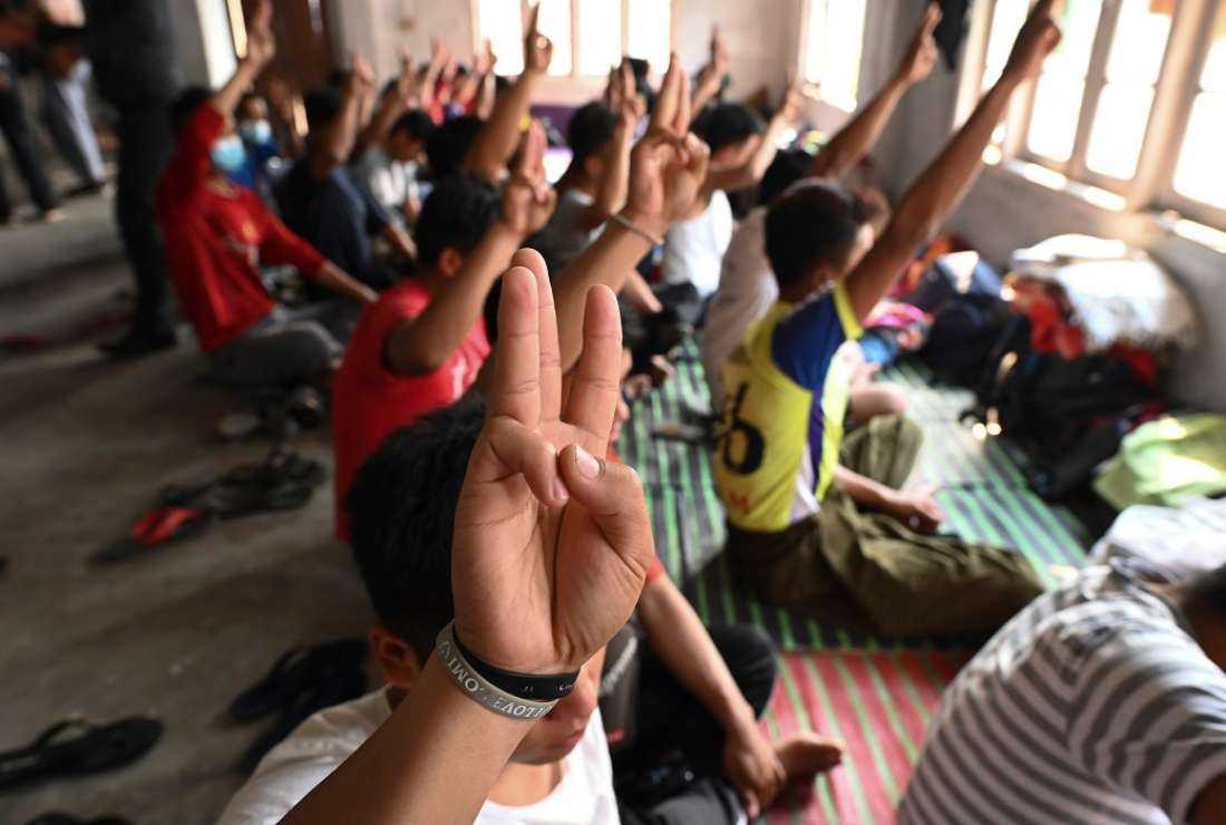 Myanmarese policemen, who fled Myanmar and crossed illegally into India, hold the three-finger salute at a temporary shelter in an undisclosed location in India's northeastern state of Mizoram on March 13, 2021.