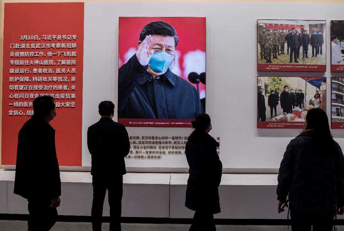 People walk past an image of China's President Xi Jinping during an exhibition about China’s fight against coronavirus at a convention center that was previously a makeshift hospital during the pandemic in Wuhan, on Jan. 15, 2021