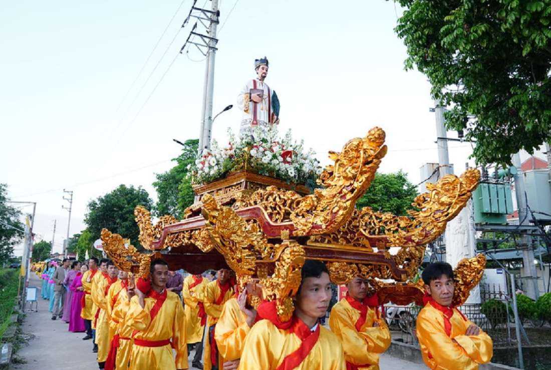 People in traditional costumes carry a statue of Martyr Peter Le Tuy around Bang So village on Oct. 10