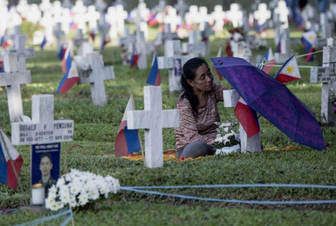 A woman visits the grave of a loved one at the Heroes Cemetery for Filipino military personnel in Manila on the eve of All Souls' Day on Oct. 31, 2018