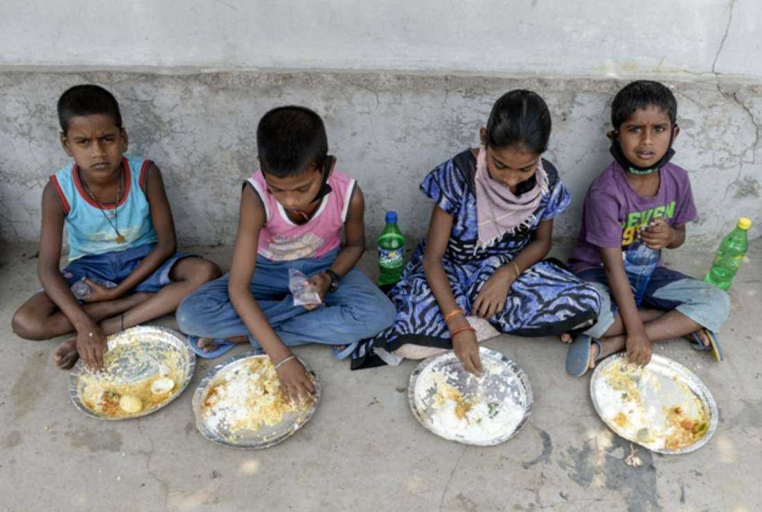 Children eat free food served by a youth charity group in a slum during a government-imposed nationwide lockdown as a preventive measure against the coronavirus in Secunderabad city on April 17, 2020