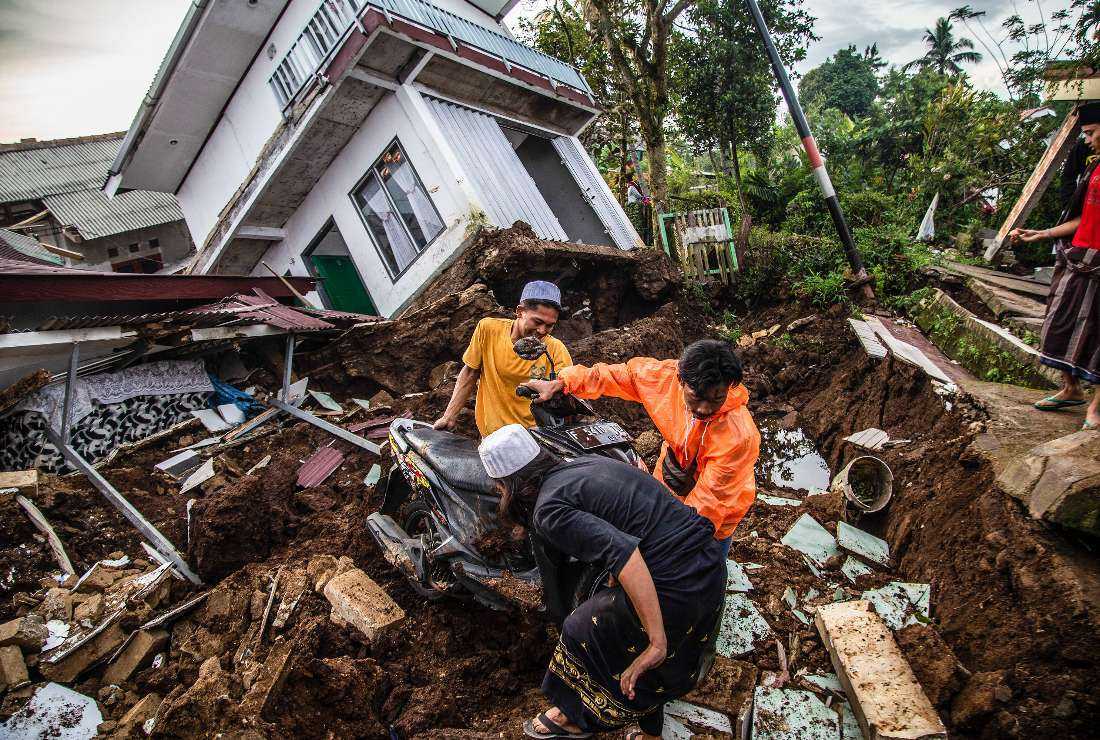 Villagers salvage items from damaged houses following a 5.6-magnitude earthquake that killed at least 162 people, with hundreds injured and others missing in Cianjur on Nov. 22