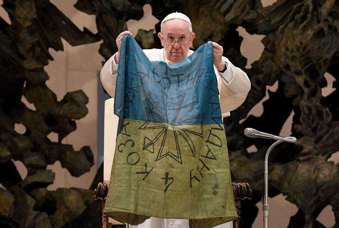 Pope Francis holding a flag of Ukraine that comes from the city of Bucha, one of the areas around Ukraine's capital from which Russian troops have withdrawn, during the weekly general audience at Paul-VI hall in the Vatican on April 6