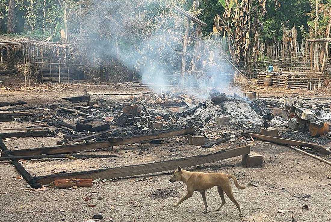 This handout photo from the humanitarian group Free Burma Rangers taken on May 3, 2022 and released on May 4 shows a dog running past the burning remains of a building after airstrikes and mortar attacks by the Myanmar military, according to the Free Burma Rangers, on a village in Doo Tha Htoo district in Myanmar's eastern Kayin state