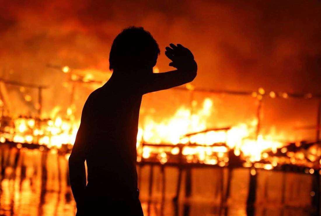 A resident looks on as a huge blaze tears through a coastal community in Mandaue City, in the Philippines on Nov 22
