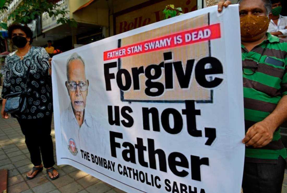 People hold a poster outside a church during memorial Mass for the Indian rights activist and Jesuit priest Father Stan Swamy, in Mumbai on July 6, 2021
