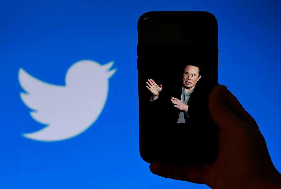 In this file photo taken on Oct. 4, a phone screen displays a photo of Elon Musk with the Twitter logo shown in the background, in Washington, DC