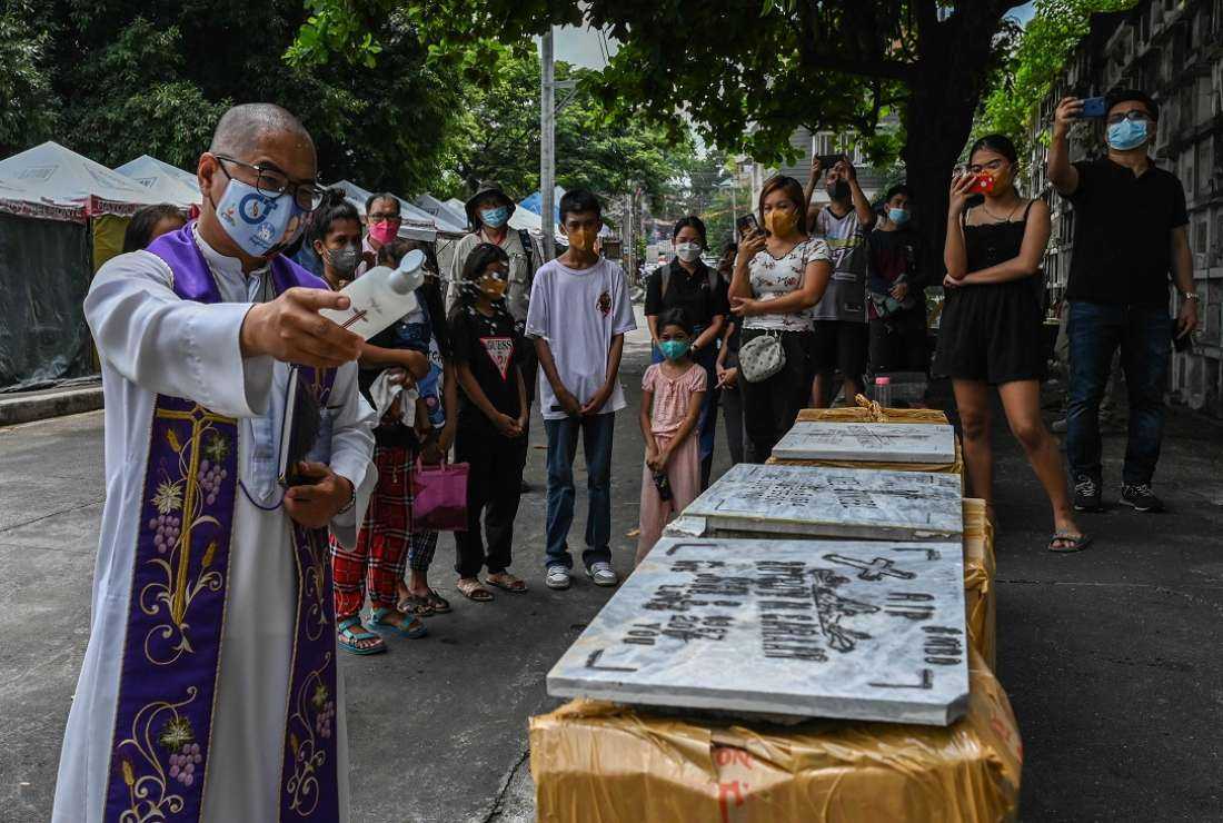 Father Flavie Villanueva prays with relatives of drug war victims during a ceremony to exhume their remains at Bagbag Cemetery in Novaliches, Metro Manila on June 10